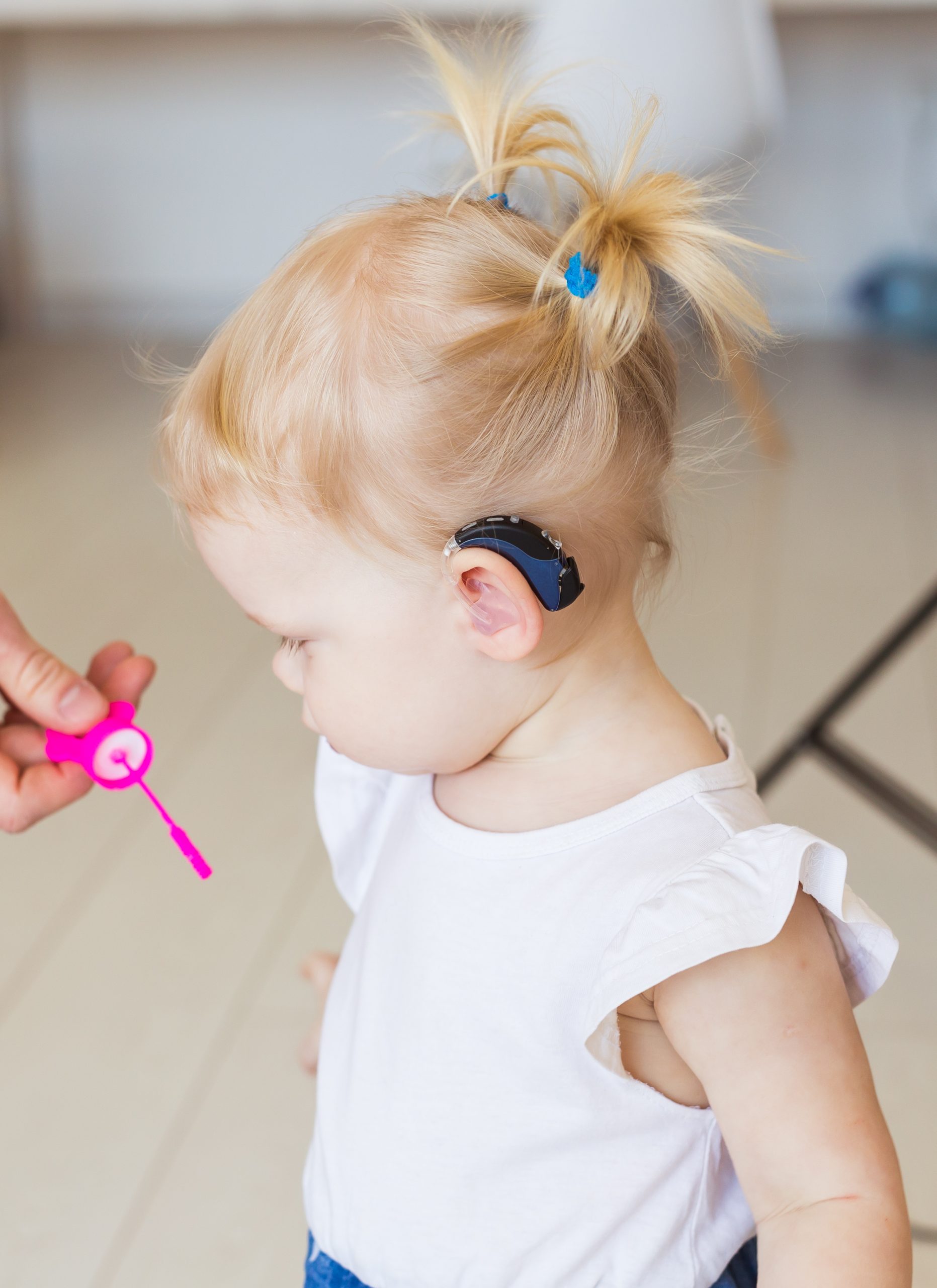 Baby girl wearing a hearing aid. Disabled child, disability and deafness concept.